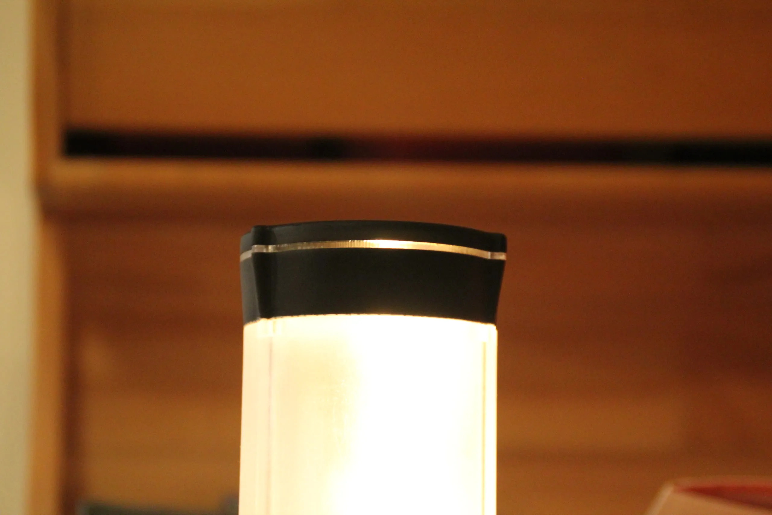 The warm filament lamp glowing in close-up against a wooden shelf.